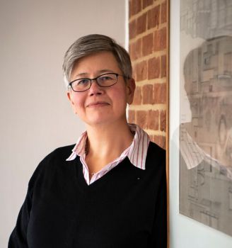 Vice-Chancellor Prof. Sasha Roseneil stands against a wall in a casual pose.