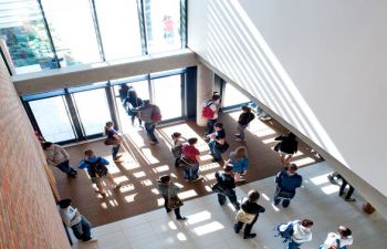 Students waiting before a lecture beneath large windows