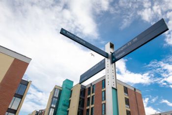 A sign post on campus indicating the directions of various student halls.