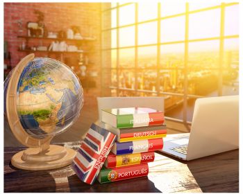 Globe and laptop next to a stack of dictionaries