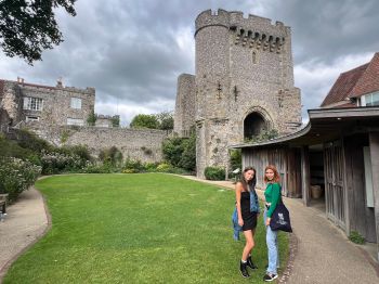 Two young women stood in front of a castle wall