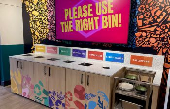 One of the new recycling banks in Eat Central, with a screen behind saying 'Use the right bin!'