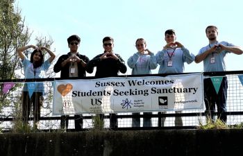 Students making heart signs by sanctuary banner