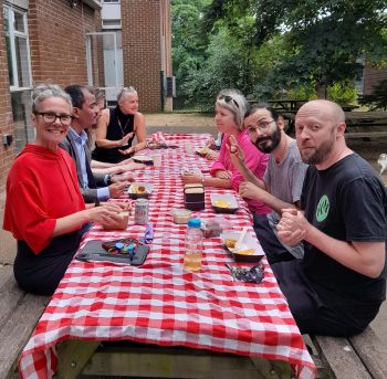 photo of people sitting at picnic table eating lunch