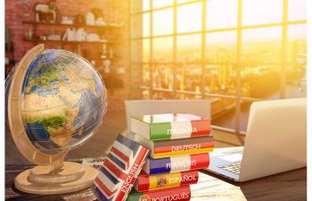 Globe and laptop next to a stack of dictionaries