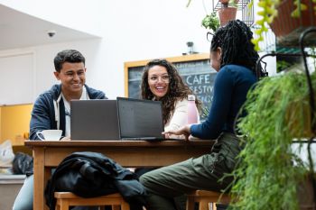 Three students chatting around a laptop