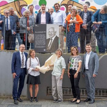 A group of individuals around the placard in commemoration of Hans Singer