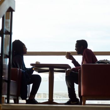 Two student in profile sit at a table.