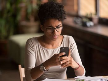 A woman looks at her phone with a concerned expression