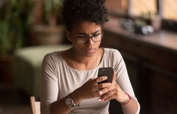 A woman looks at her phone with a concerned expression