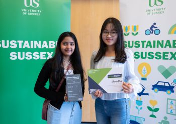 Green Impact Project Assistants showcasing their awards in front of sustainability and Green Impact banners