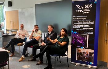 Four speakers (three male and one female) sat at front of room answering questions