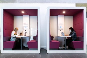 students sat in a booth working on their laptops