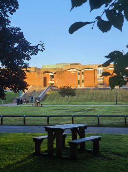 A photo of the Library building at University of Sussex with a picnic bench in the foreground