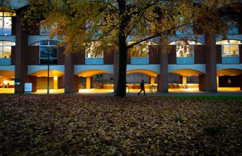 White arches beneath a red brick building lit up as darkness falls.