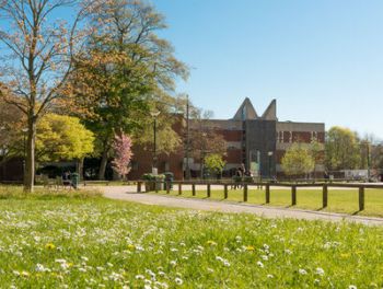 Photo of campus buildings, trees, grass and paths