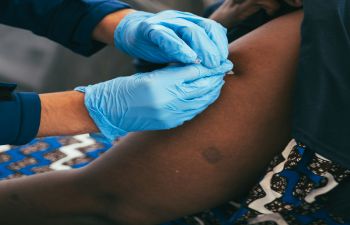 A woman's arm being vaccinated by a medic