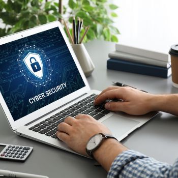 A person working on a laptop displaying a cybersecurity graphic.