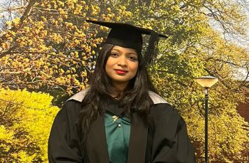 Graduating student smiling and wearing gown and mortar board