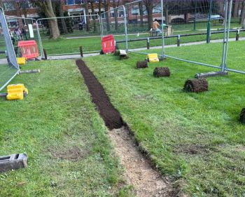 Fences around a patch of grass which has been dug to lay cabling underneath