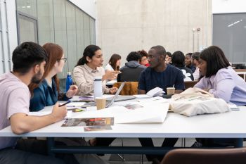 Students sat around a table with notes on,all looking at one student who is leading the conversation