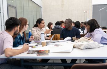 Students sat around a table with notes on,all looking at one student who is leading the conversation