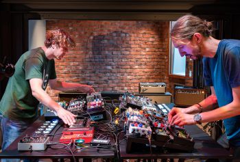 Two people playing effects pedals