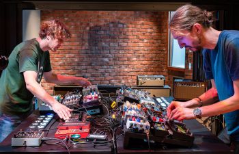 Two people playing effects pedals