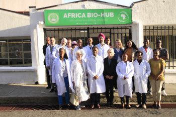 A group of researchers pictured together in front of a green sign reading Africa Bio Hub