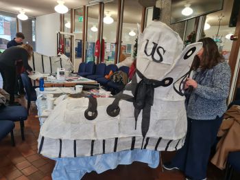 Students working on large paper shoe sculpture