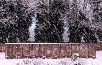 The University of Sussex Logo Board at the start of the campus covered in snow.