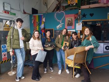 Group of students smiling at the camera and holding props used in the workshop