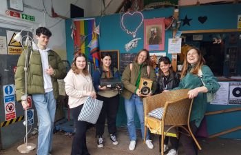 Group of students smiling at the camera and holding props used in the workshop