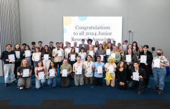 The 2024 cohort of Junior Research Associates smiling at the camera and holding their certificates of completion