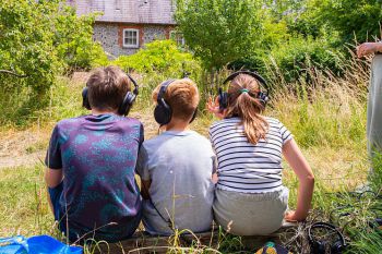 Children with headphones on looking at a grassy scene