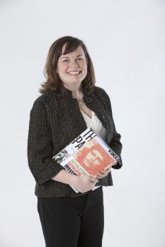 A photo of Dr Anne-Marie Angelo smiling at camera and holding some books