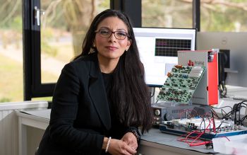 Elizabeth Rendon-Morales sits at a desk in front of electrical equipment