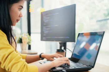 a woman in a yellow top working on a laptop