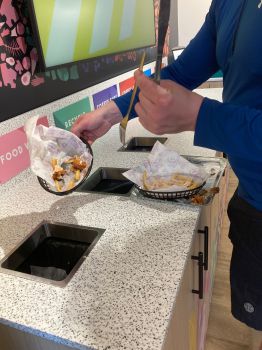 Diner's hands as they scrape food waste from their plate into the food waste bin, one of six recycling bins in Eat Central