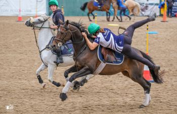 A female mounted games athlete pulling herself onto a moving horse