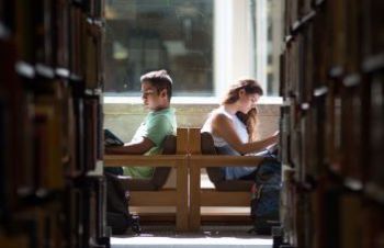 Two students sitting in chairs at the Library