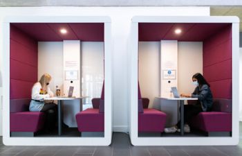 students sat in a booth working on their laptops