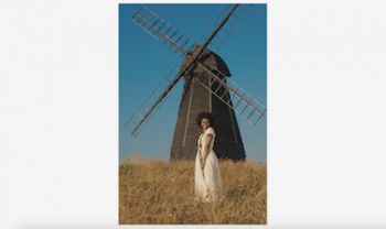 Woman wearing indigenous Nigerian clothing standing in front of a black windmill