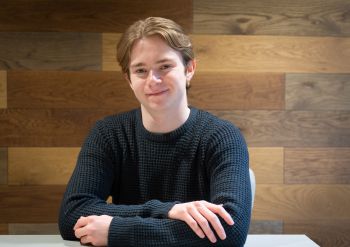 Person seated with arms crossed and smiling at the camera