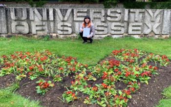 Huyen Le in front of the University of Sussex sign