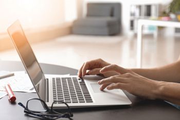 A person types at a laptop.