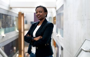 Bridget Kauma stands with her amrs folded looking towards the camera