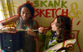 Photograph of Hannah and Isla. Hannah holds an amp box and flute while Isla holds a flute and paint pallet. The words 'skank and sketch' are drawn over the top of the image in red, green and yellow