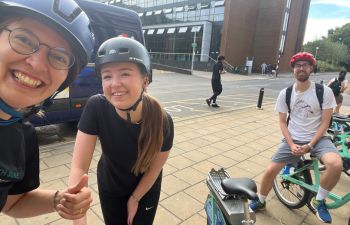 Maighsi and a few of their work colleagues posing together after cycling to work, with helmets on.