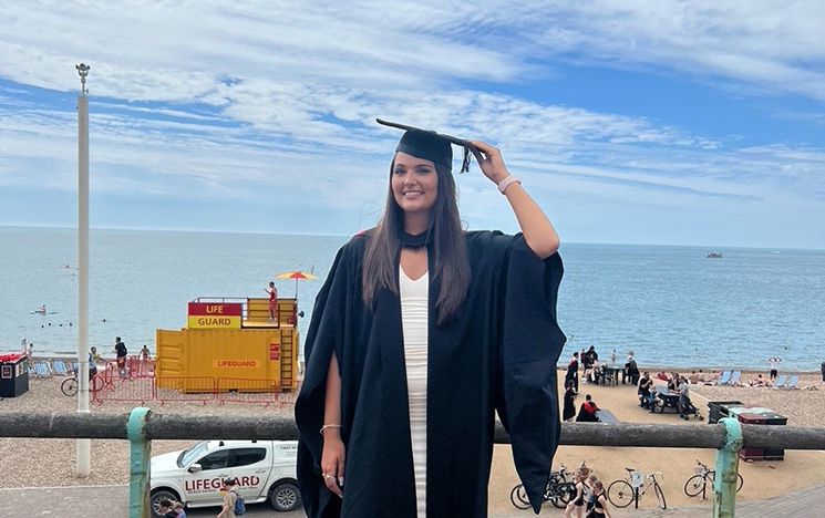 Heather McGee in her graduation gown on Brighton seafront blog image